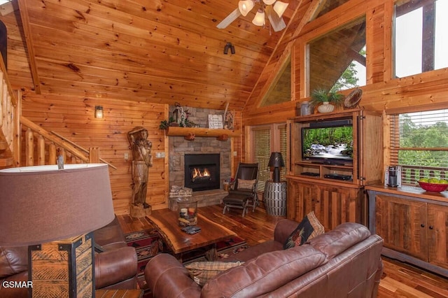 living room with wooden walls, a fireplace, wooden ceiling, ceiling fan, and wood-type flooring