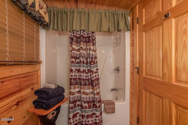 bathroom with shower / bath combo with shower curtain and wooden walls