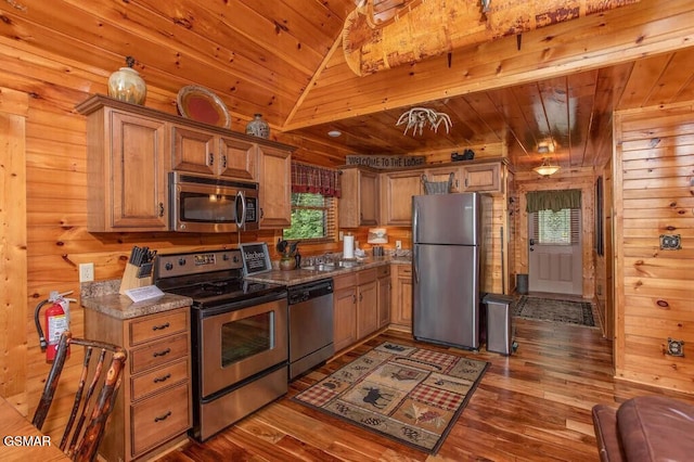 kitchen with appliances with stainless steel finishes, wood ceiling, wooden walls, and dark wood-type flooring