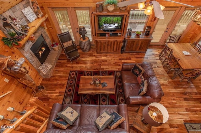 living room featuring ceiling fan, a stone fireplace, and hardwood / wood-style floors