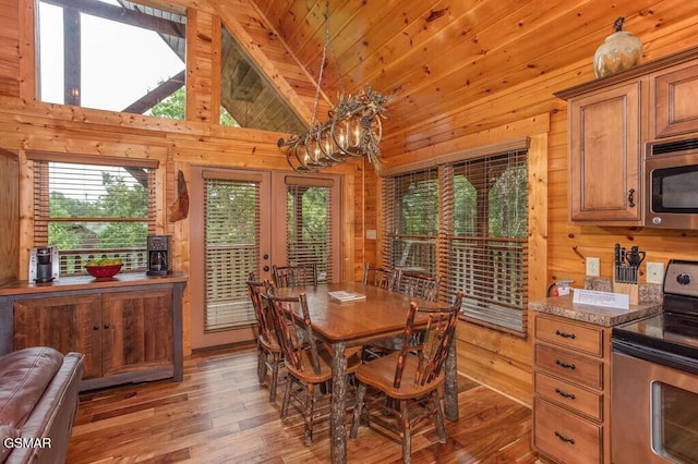 dining room featuring french doors, wooden walls, high vaulted ceiling, wood-type flooring, and wooden ceiling