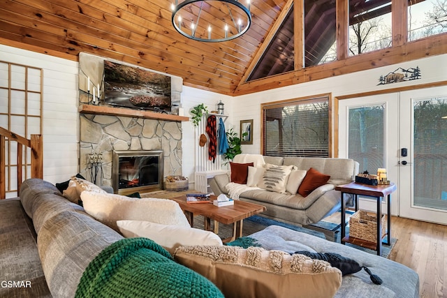 living area featuring wooden ceiling, wood finished floors, a stone fireplace, french doors, and high vaulted ceiling