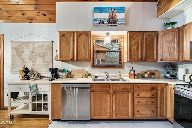 kitchen featuring stainless steel appliances, a sink, light countertops, and brown cabinets