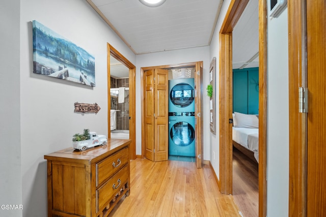 hall with stacked washer / dryer and light wood-style floors