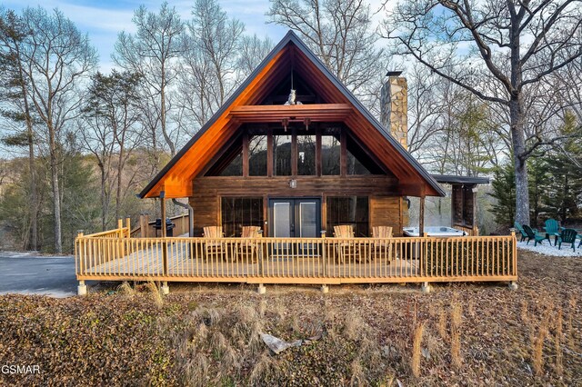 back house at dusk featuring a wooden deck and a hot tub