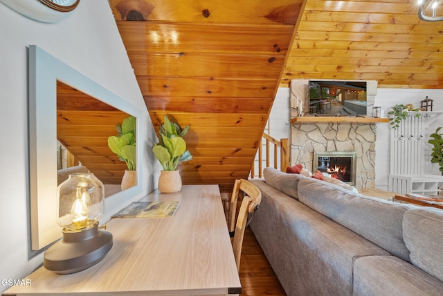 living room with wood finished floors, a stone fireplace, and stairs