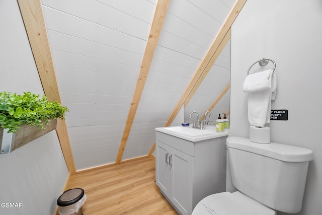 half bathroom featuring wood finished floors, toilet, vanity, and lofted ceiling with beams