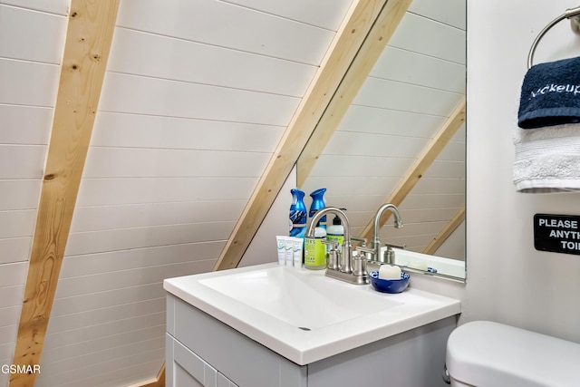 half bath with toilet, beamed ceiling, and vanity