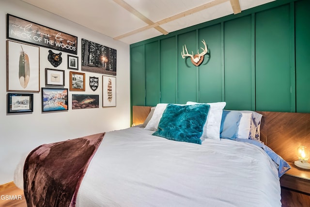 bedroom with beamed ceiling and a decorative wall