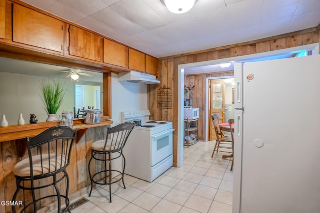 250 Cartertown Rd, Gatlinburg, TN 37738 - kitchen featuring brown cabinetry, white appliances, light tile patterned floors, wood walls, and under cabinet range hood