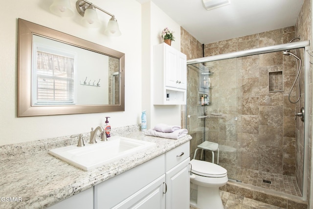 bathroom with a shower with shower door, toilet, and vanity