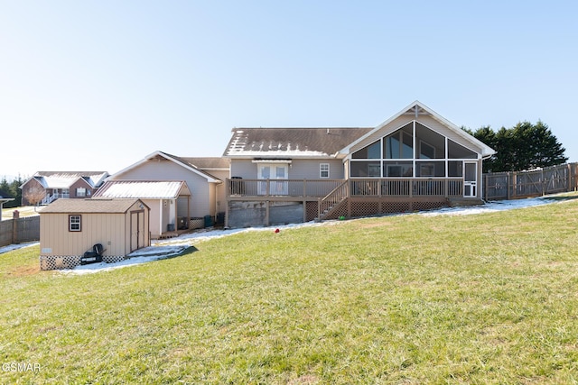 back of property featuring a deck, a sunroom, a yard, and a storage unit