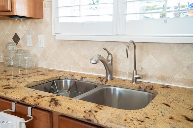 details featuring light stone countertops, sink, and tasteful backsplash