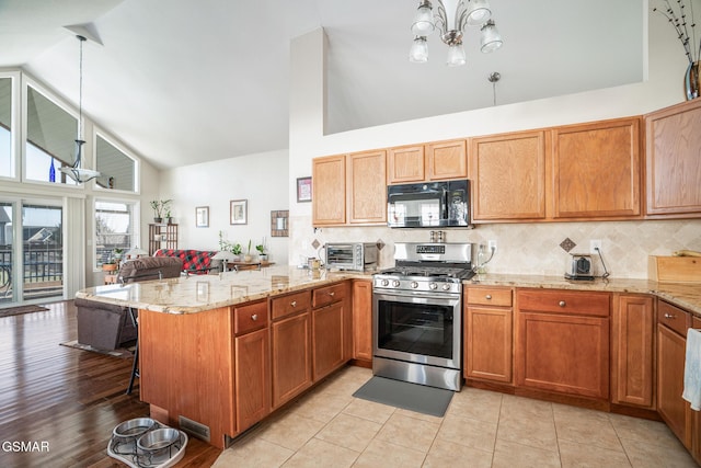 kitchen featuring tasteful backsplash, gas stove, kitchen peninsula, hanging light fixtures, and high vaulted ceiling