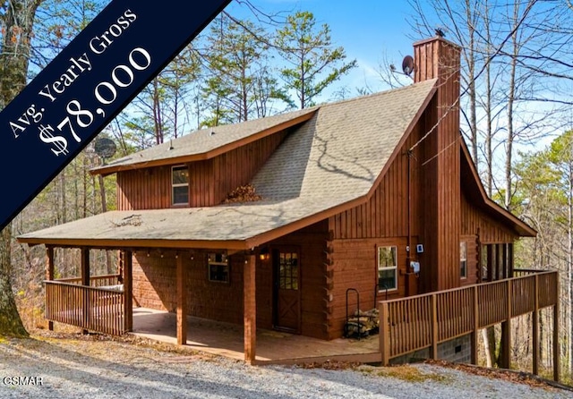 back of property featuring a chimney, log exterior, and roof with shingles