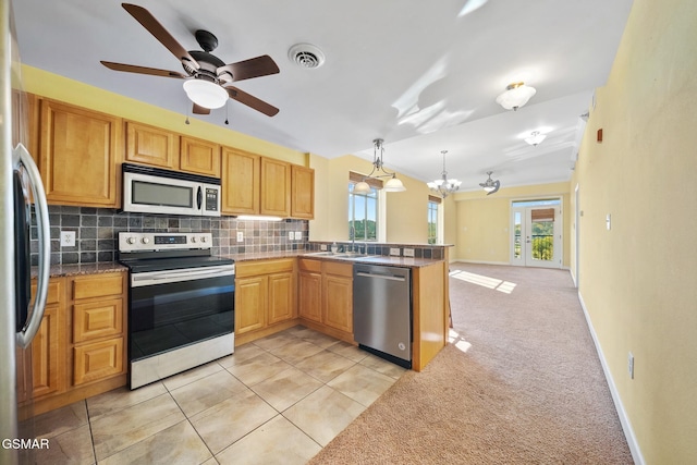 kitchen with hanging light fixtures, tasteful backsplash, light carpet, ceiling fan with notable chandelier, and appliances with stainless steel finishes