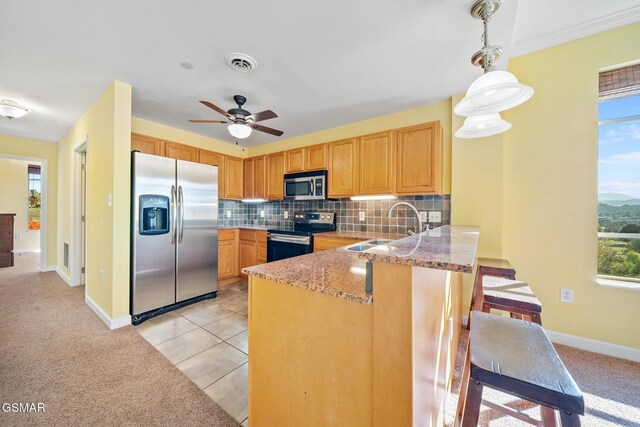 kitchen featuring sink, stainless steel appliances, kitchen peninsula, decorative light fixtures, and light tile patterned flooring