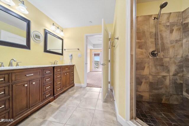 bathroom with tile patterned flooring, vanity, and a tile shower