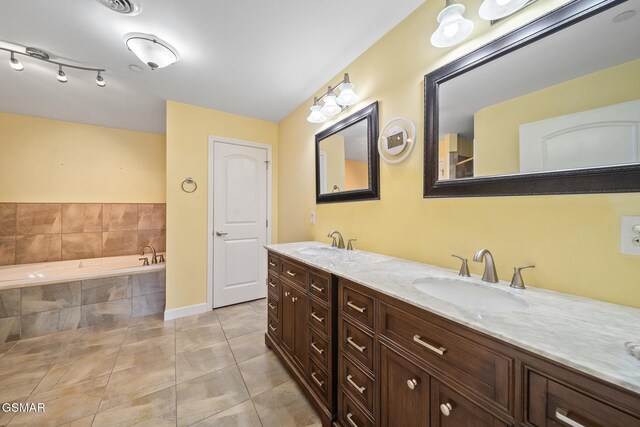 bathroom with tile patterned floors, tiled tub, and vanity