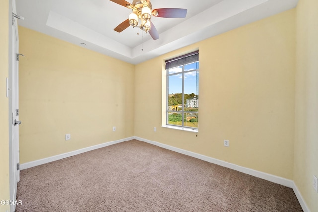 spare room featuring carpet, a raised ceiling, and ceiling fan