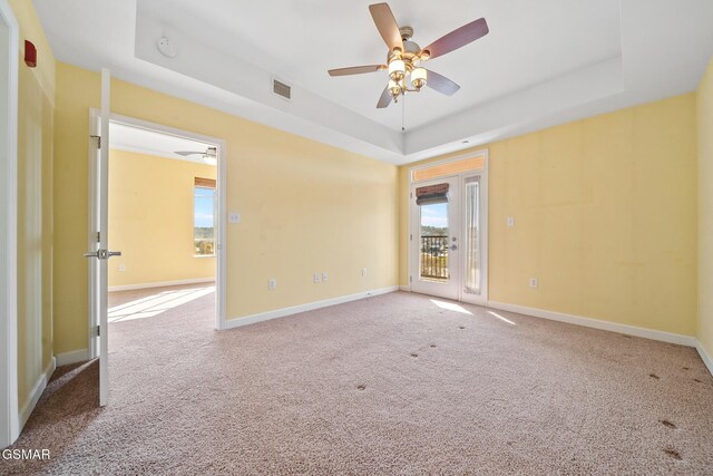 carpeted spare room with ceiling fan and a tray ceiling