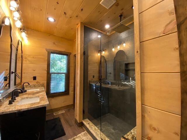 bathroom with wood ceiling, wood-type flooring, a shower with door, vanity, and wood walls