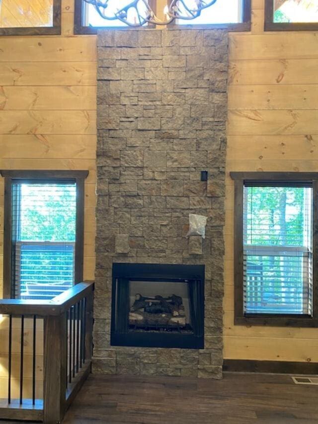 unfurnished living room featuring dark hardwood / wood-style flooring, a wealth of natural light, and a stone fireplace