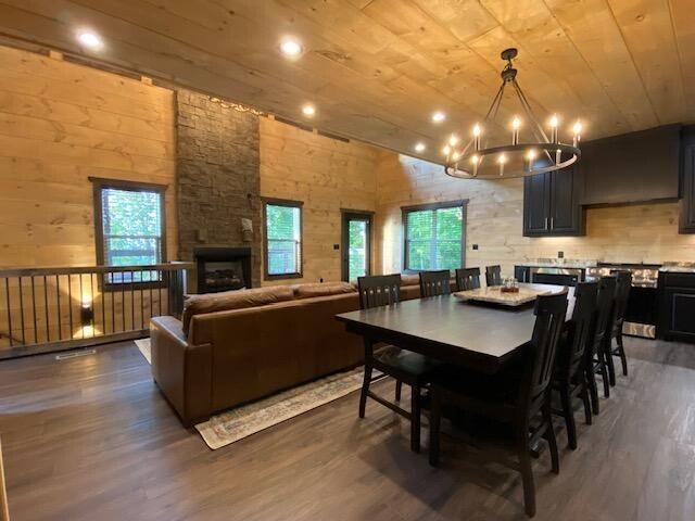 dining room featuring a fireplace, a towering ceiling, dark wood-type flooring, wood ceiling, and a chandelier