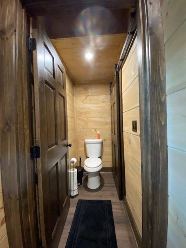 bathroom with hardwood / wood-style flooring, toilet, wood walls, and wood ceiling