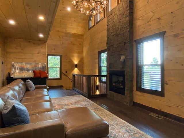 living room with an inviting chandelier, a stone fireplace, wooden ceiling, dark hardwood / wood-style flooring, and high vaulted ceiling