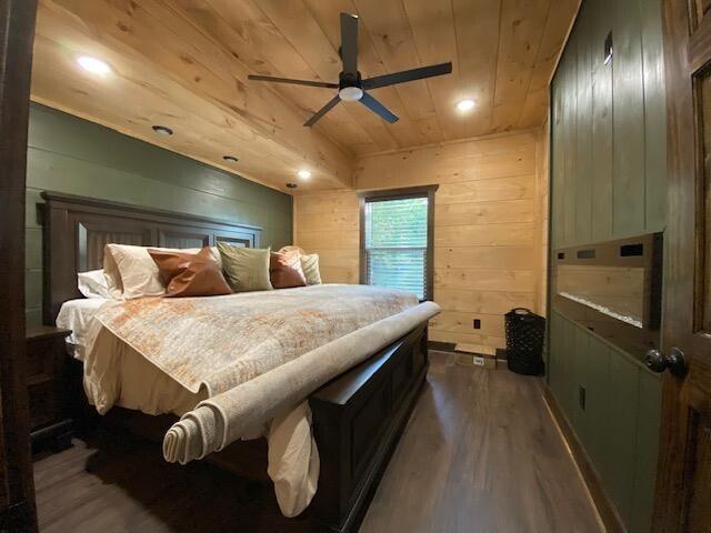 bedroom featuring ceiling fan, wooden ceiling, dark hardwood / wood-style floors, and wood walls