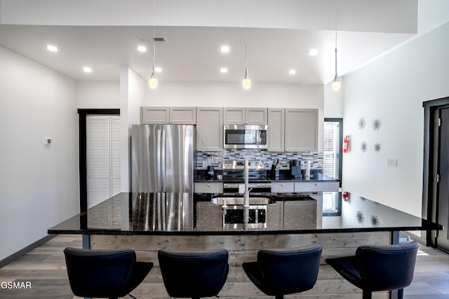 1349 N Baden Dr, Gatlinburg, TN 37738 - kitchen with stainless steel appliances, gray cabinets, a center island with sink, wood finished floors, and decorative backsplash