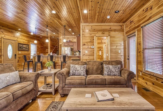 living room with light hardwood / wood-style floors, wooden ceiling, and wood walls