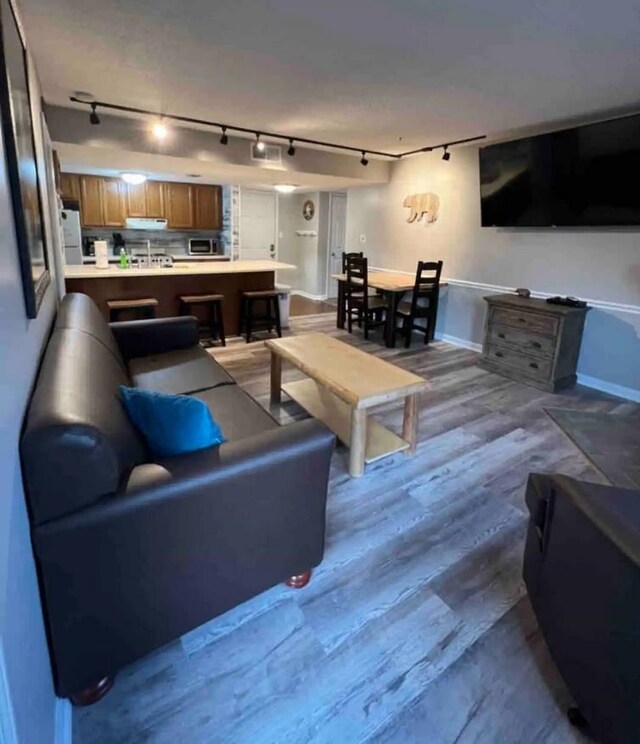 living room with rail lighting and light wood-type flooring