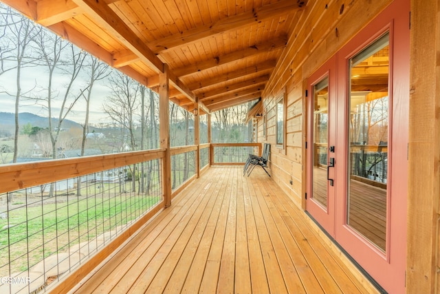 unfurnished sunroom with a healthy amount of sunlight, wooden ceiling, a mountain view, and beam ceiling