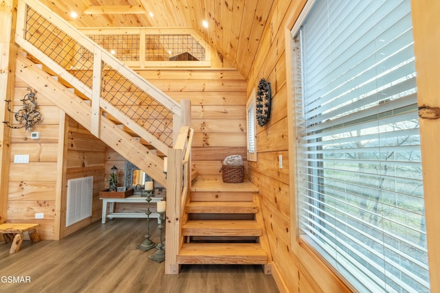 staircase featuring wooden ceiling, wooden walls, visible vents, and wood finished floors