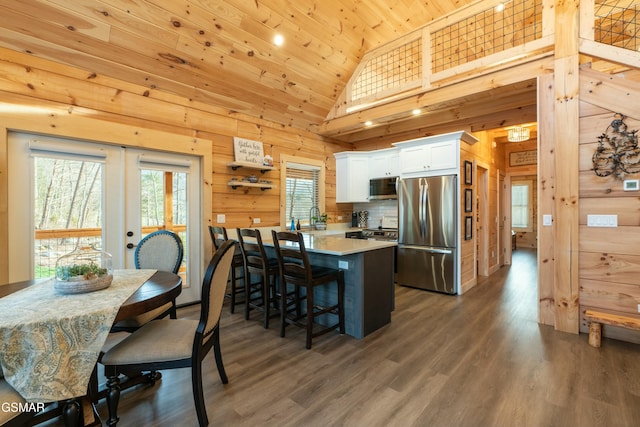 kitchen featuring wooden walls, appliances with stainless steel finishes, light countertops, french doors, and white cabinetry