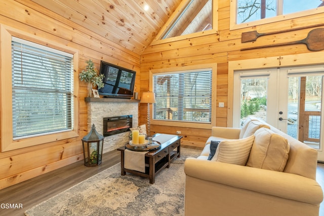 living room with wooden ceiling, wood walls, wood finished floors, and a stone fireplace