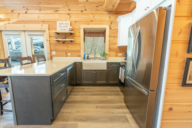 kitchen featuring stainless steel appliances, a breakfast bar, a peninsula, a sink, and light wood finished floors