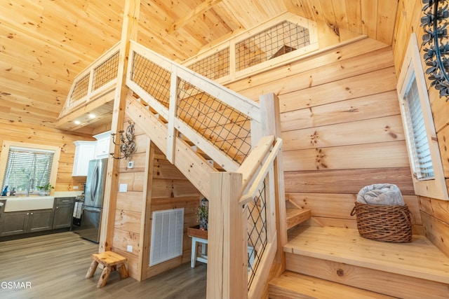 interior space with wood ceiling, high vaulted ceiling, wood walls, and visible vents