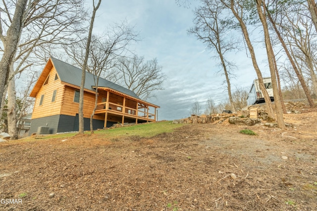 back of house with metal roof, central AC unit, and a wooden deck