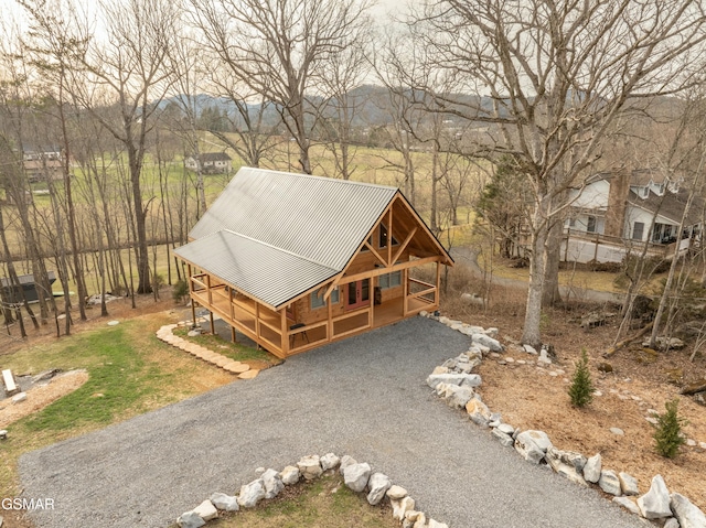 view of front of house featuring gravel driveway, a porch, and metal roof