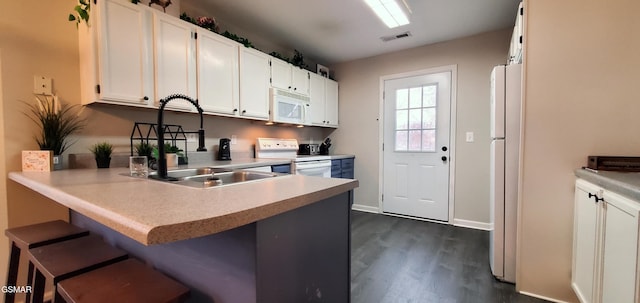 kitchen with white appliances, visible vents, a peninsula, white cabinetry, and a sink