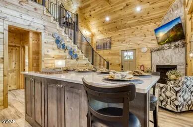 937 Pine Valley Way, Sevierville, TN 37862 - bar area featuring high vaulted ceiling, wood walls, stairway, light wood-style flooring, and a premium fireplace