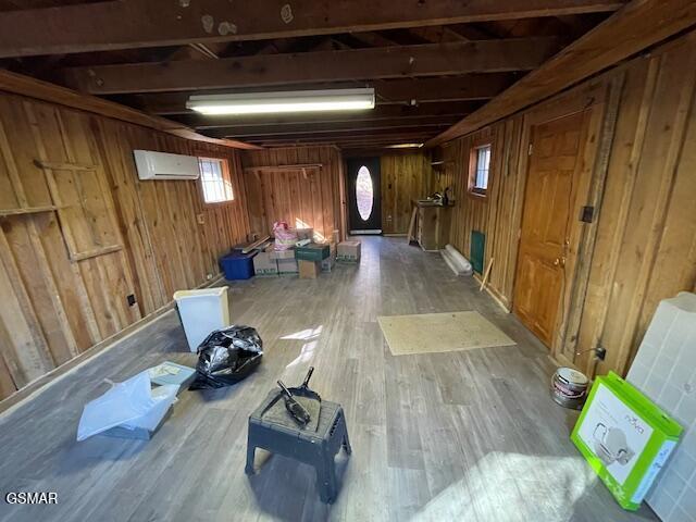 basement featuring wood-type flooring and a wall mounted air conditioner