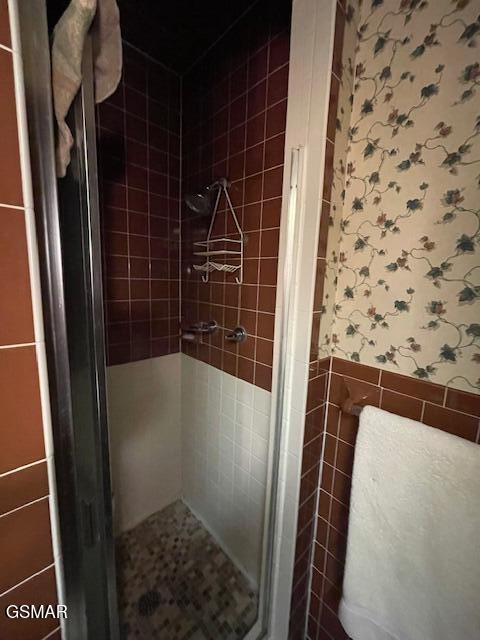 bathroom featuring an enclosed shower and tile walls