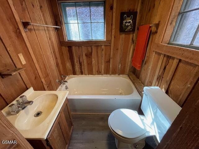 bathroom featuring toilet, vanity, a bathtub, and wooden walls