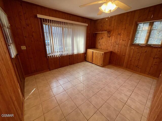 empty room with light tile patterned floors and wooden walls