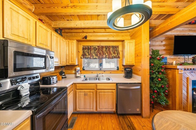 kitchen with stainless steel appliances, sink, rustic walls, and beamed ceiling