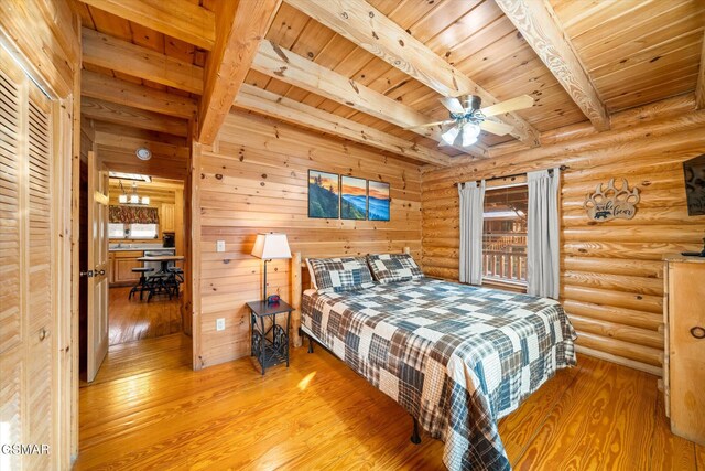 bedroom featuring beam ceiling, wooden ceiling, log walls, and light wood-type flooring